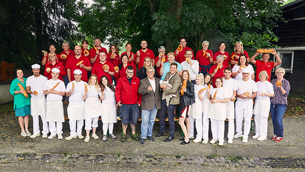 Das Weinberger Team lacht in die Kamera, manche halten Gebäckstücke in die Höhe